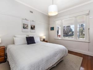 a white bedroom with a bed and a window at Dingle On Barclay in Port Fairy
