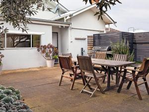 a patio with a wooden table and chairs and a grill at Dingle On Barclay in Port Fairy
