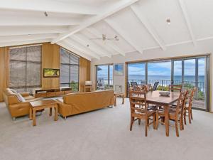 ein Wohnzimmer mit einem Tisch, Stühlen und Fenstern in der Unterkunft East Beach House in Port Fairy