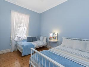 a blue room with two beds and a couch at Ginabella in Port Fairy