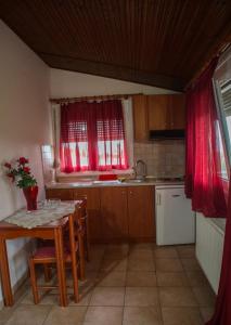 een keuken met een tafel, een wastafel en rode gordijnen bij Drosia Hotel in Kato Loutraki