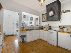 una cocina con armarios blancos y un reloj en la pared en Gipps Getaway, en Port Fairy