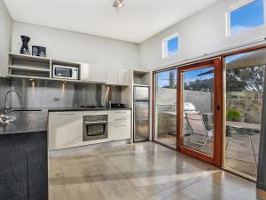 a kitchen with stainless steel appliances and a patio at Hearns Beachside Villa 1 in Port Fairy