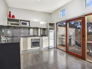 a kitchen with white appliances and a sliding glass door at Hearns Beachside Villa 2 in Port Fairy