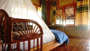 a bedroom with a bed and a chair and a window at Ricky's Beach House in Pasarsungai-nyala