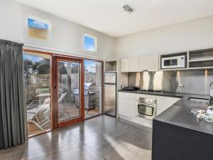 a large kitchen with white appliances and a patio at Hearns Beachside Villa 3 in Port Fairy