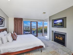 a bedroom with a large bed and a fireplace at Hearns Beachside Villa 4 in Port Fairy
