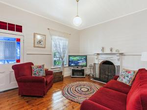 a living room with two red chairs and a television at Hillingden in Port Fairy