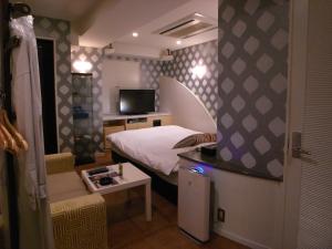 a small room with a bed and a television at HOTEL Q in Tokyo
