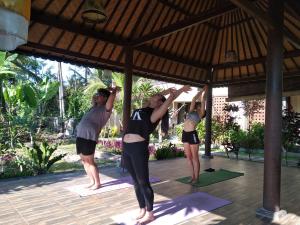 eine Gruppe von Leuten, die Yoga auf einer Yoga-Terrasse machen in der Unterkunft Demank Hidden Guesthouse in Ubud