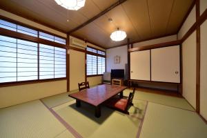 Habitación con mesa, sillas y ventanas. en Kiyoshigekan, en Kusatsu