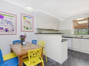 a kitchen with a wooden table and yellow chairs at Killead On East in Port Fairy