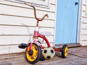 un triciclo infantil con una pelota de fútbol sentado al lado de una casa en Kinsale Cottage, en Port Fairy