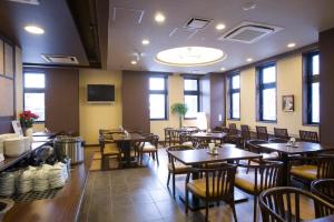 a restaurant with wooden tables and chairs and windows at Hotel Route-Inn Morioka Minami Inter in Morioka