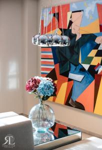 a vase with flowers in front of a painting at Hotel RL Anibal in Linares