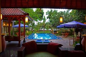 a swimming pool with a couch and umbrellas at Bali au Naturel in Tejakula