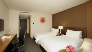 a hotel room with two beds and a desk at LOTTE City Hotel Gimpo Airport in Seoul