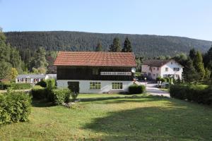 un grand bâtiment blanc avec un toit rouge dans l'établissement Camping Les Granges Bas - Mobilhomes - Tiny House, à Gérardmer