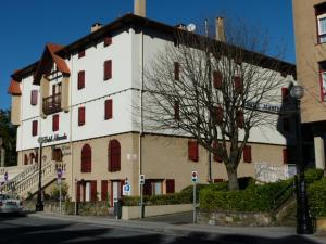 a large white building with red windows on a street at Hotel Alameda in Zarautz