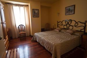 a bedroom with a bed with a wooden floor and a window at Hotel Alameda in Zarautz