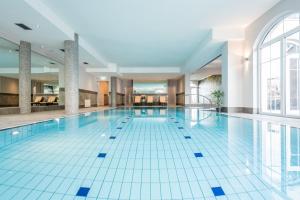 a large swimming pool in a building with a large window at Parkhotel Hachenburg in Hachenburg