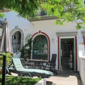 um pátio com cadeiras, uma mesa e um guarda-sol em Little Venice Apartment in Puerto de Mogan em Puerto de Mogán