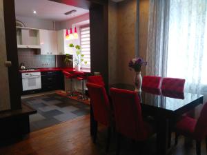 Apartment on Dubenskaya street في روفنو: مطبخ مع طاولة طعام وكراسي حمراء