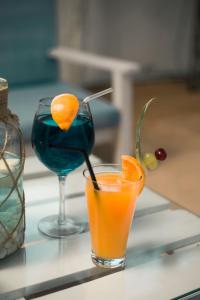 two glasses of orange juice and a martini on a table at Stella Rina in Grand-Baie