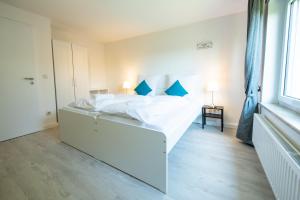 ein Schlafzimmer mit einem großen weißen Bett mit blauen Kissen in der Unterkunft FeWo Meersburg in Meersburg