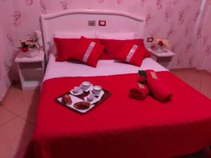 un letto rosso con un vassoio di cibo sopra di hotel tiffany a Varcaturo