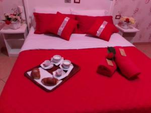 Una cama roja con una bandeja de comida. en hotel tiffany, en Varcaturo