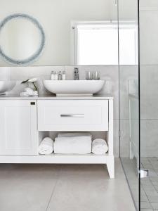 a white bathroom with a sink and a mirror at The Marine Hermanus in Hermanus