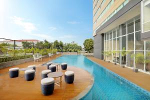 马卡萨Mercure Makassar Nexa Pettarani的一座带凳子的建筑屋顶上的游泳池