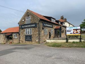 a stone building with a sign in front of it at Poacher's Barn in Cayton