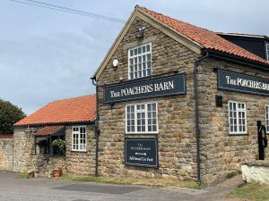 a stone building with a sign for the powerhouse barn at Poacher's Barn in Cayton +5 photos