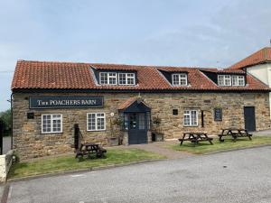 a building with two picnic tables in front of it at Poacher's Barn in Cayton