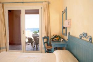 TH Costa Rei - Free Beach Resort في مونتي ناي: غرفة نوم بسرير وطاولة وبلكونة