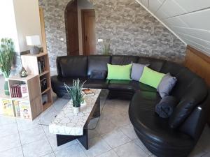 a black leather couch in a living room with a table at Ferienwohnung Frischkorn in Steinau an der Straße