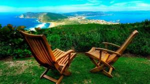 dos sillas de madera sentadas en la hierba cerca del océano en Apartamentos SEOANE, en Finisterre