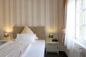 ein Schlafzimmer mit einem Bett und zwei Tischen mit Lampen in der Unterkunft Hotel Am Schloss Biebrich in Wiesbaden