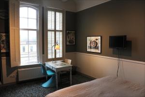 a bedroom with a desk and a bed and a tv at Villa Augustus in Dordrecht