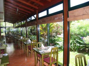 a dining room with tables and chairs and windows at Hotel Jardim Atlantico in Calheta