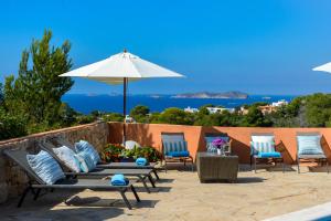 a group of chairs and an umbrella on a patio at CAN COSTA in Cala Vadella