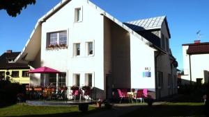 a white house with tables and chairs in front of it at Pokoje Klaudia in Darłowo