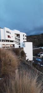 a white building on top of a hill next to the ocean at Sea loft with a huge bed in Icod de los Vinos