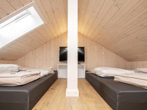 two beds in a attic room with a tv at 14 person holiday home in Idestrup in Marielyst
