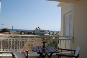 een tafel en stoelen op een balkon met uitzicht op de oceaan bij Villa Vourda in Marathokampos