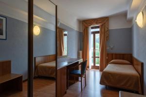 サン・ゼーノ・ディ・モンターニャにあるPark Hotel Jolandaのベッド、デスク、鏡が備わる客室です。
