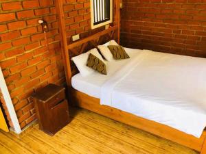 a bed in a room with a brick wall at Rovenluck Eco Cabana in Weligama