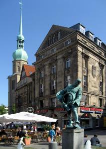 a statue of a man standing in front of a building at Sunday Hotel Dortmund City in Dortmund